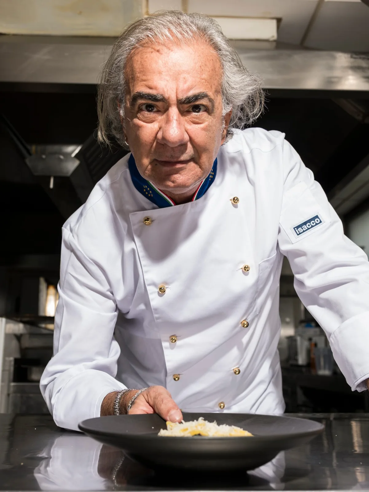 Lo chef rifinisce un piatto al passe.