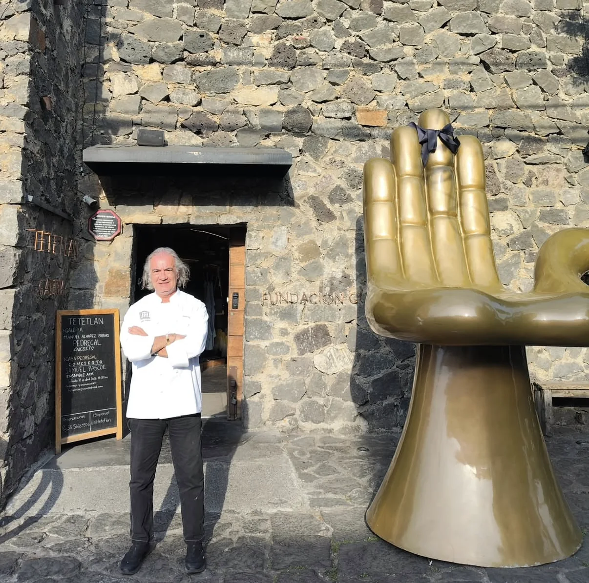Lo chef davanti a Tetetlán, accanto alla scultura della mano dorata di Pedro Friedeberg.