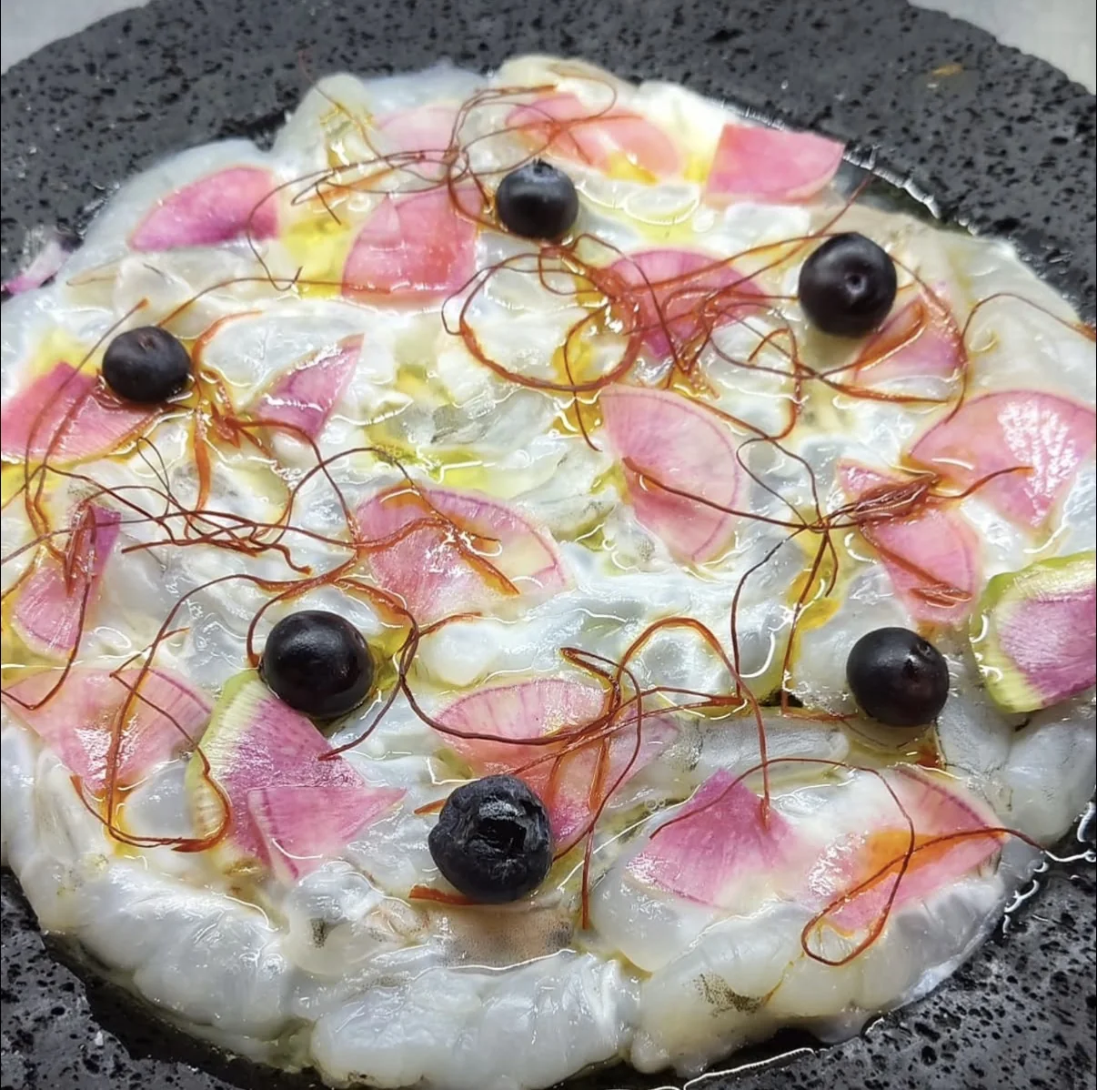 Crudo di gambero con petali di rapa rossa, mirtilli e fili di peperoncino.