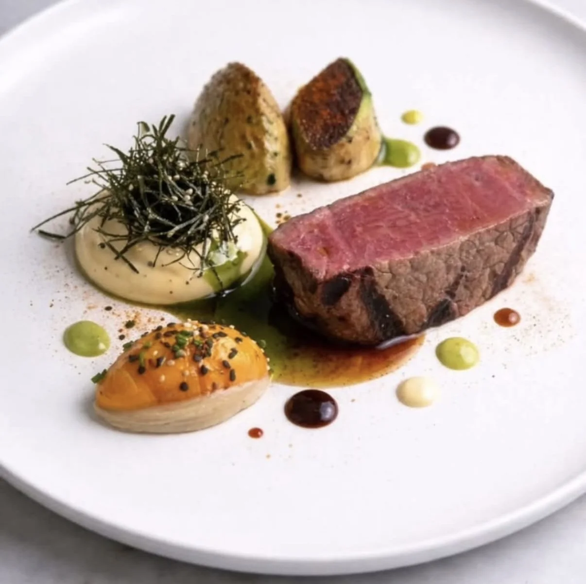 Filetto scottato con creme vegetali, polveri e gocce di riduzione.