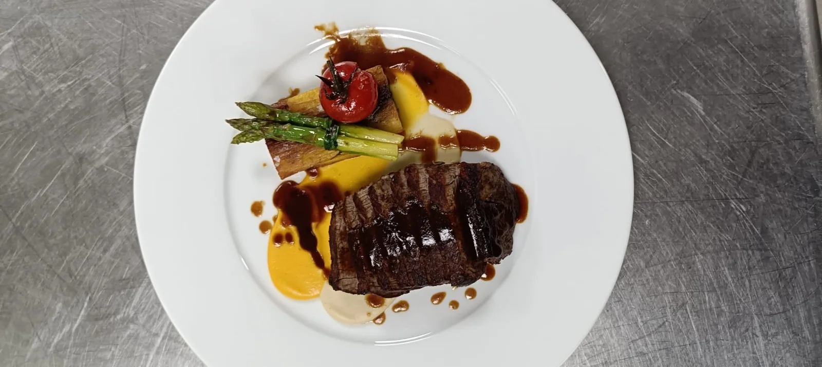 Tagliata di manzo glassata con asparagi, pomodorino confit e due creme.