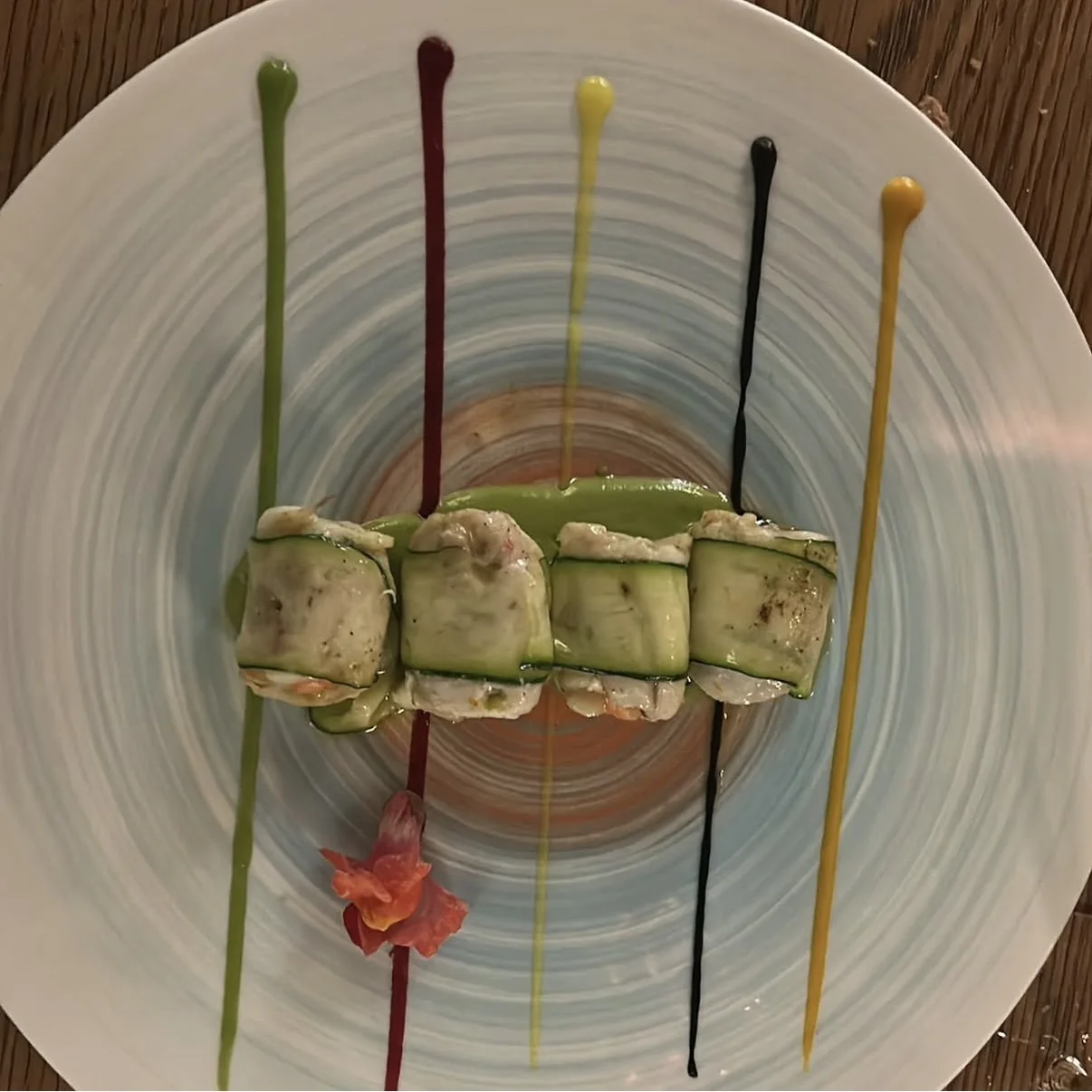 Involtini di zucchine su un arcobaleno di salse colorate.